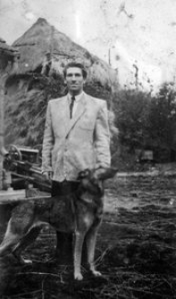 Jan Pacucha na tle sterty z sianem nakrytej przenośnym słomianym dachem