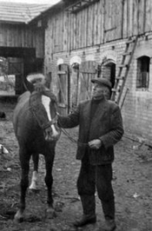 Jan Grudzień na tle zabudowań gospodarskich